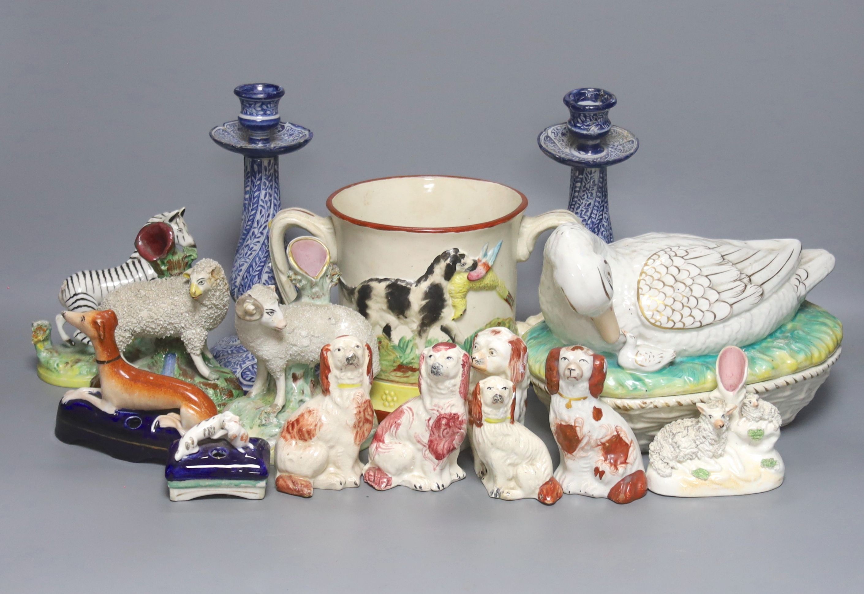 A Staffordshire pottery ‘duck’ tureen and cover, 23cm, a pair of faience candlesticks, Staffordshire figures of dogs, sheep and a zebra and a two handled loving mug